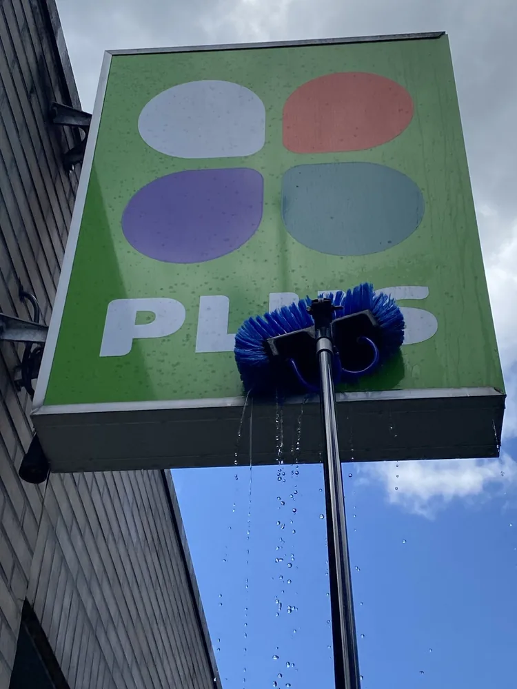 Reclame-uiting van PLUS wordt handmatig gereinigd met een borstel